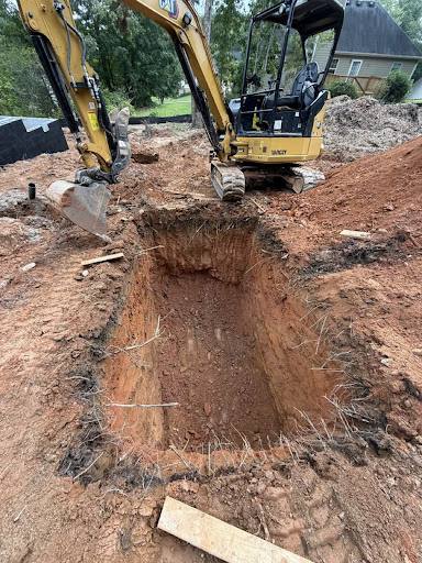 Excavator digging a foundation trench on a residential lot.