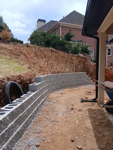 Curved block retaining wall under construction against an excavated slope.
